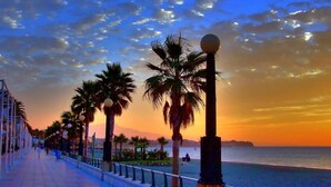 A coastal promenade with palm trees and street lamps during sunset. - Hotel Mare Estepona (Estepona)