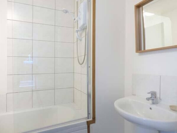 A bathroom with a glass shower enclosure and a white sink.
