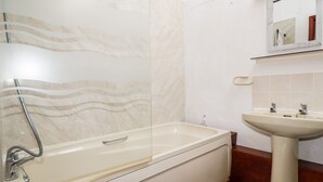 A bathroom with a bathtub, a sink, and a mirror. - Ravens Croft (Bodmin)