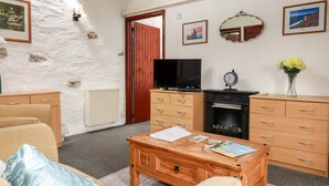 A cozy living room with a fireplace, wooden furniture, and a television. - Ravens Croft (Bodmin)