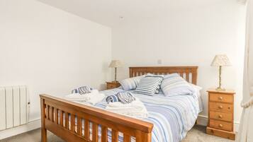 A neatly made bed with striped bedding, a wooden headboard, and two bedside tables with lamps.