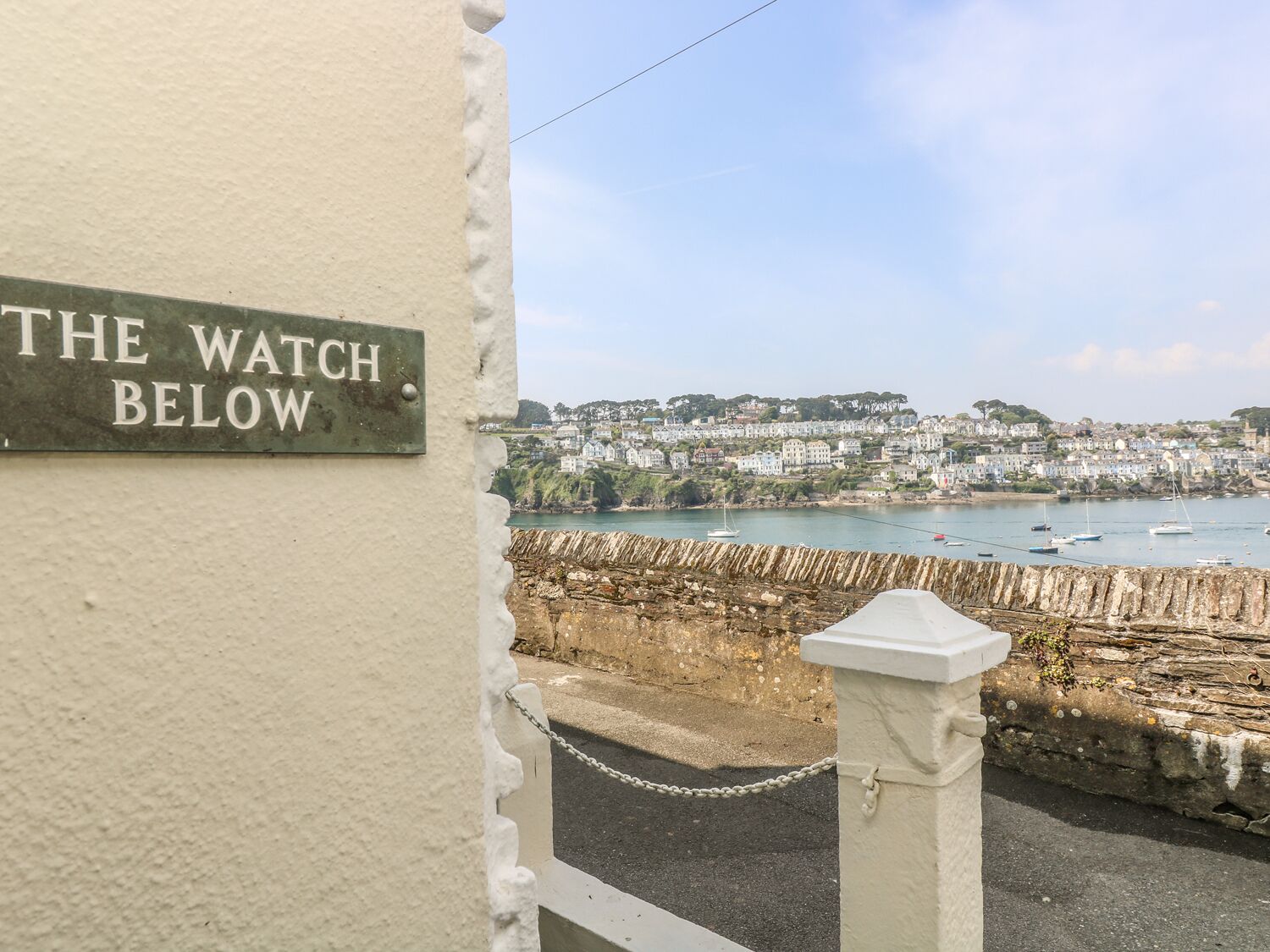 A sign reading "THE WATCH BELOW" with a coastal town view in the background.