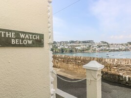 A sign reading "THE WATCH BELOW" with a coastal town view in the background.