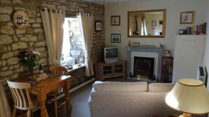 Ein gemütliches Wohnzimmer mit Steinwand, Kamin, Fernseher und Essbereich mit Tisch und Stühlen.