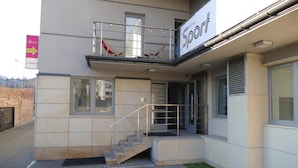 Un hostal moderno con balcón, una escalera y un letrero que indica un restaurante cercano.