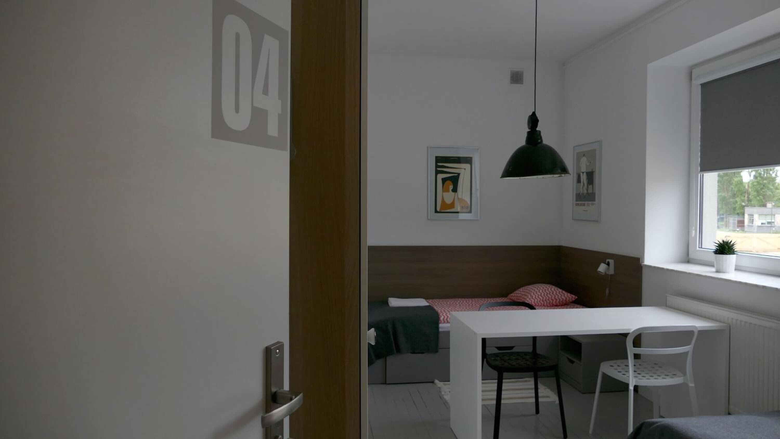 A room with a bed, a desk, a chair, and a window.