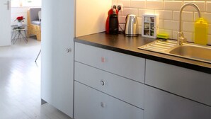 Una cocina moderna con armarios blancos, encimera negra y pileta de acero inoxidable.
