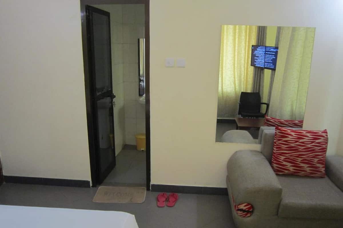 Una habitación de hotel con cama, sofá, una mesita y televisor instalado en la pared.