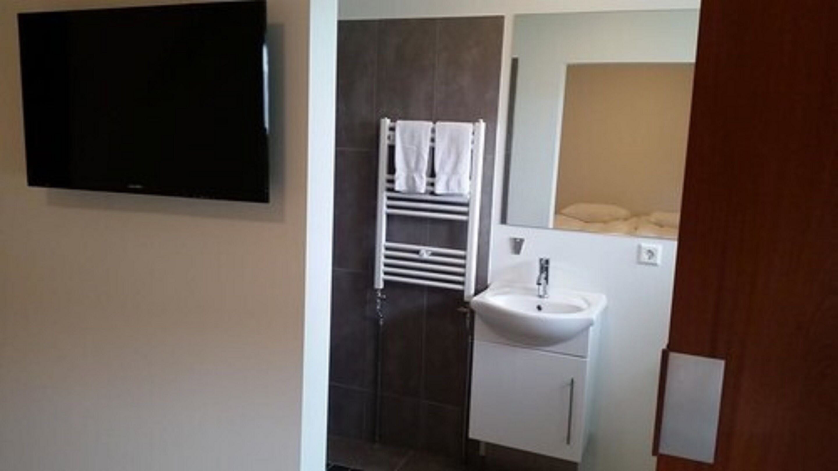 Une salle de bain avec un lavabo blanc, un porte-serviettes et un miroir.