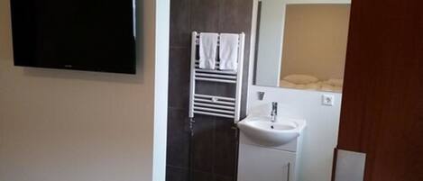 Un baño con lavamanos blanco, toallero y espejo.