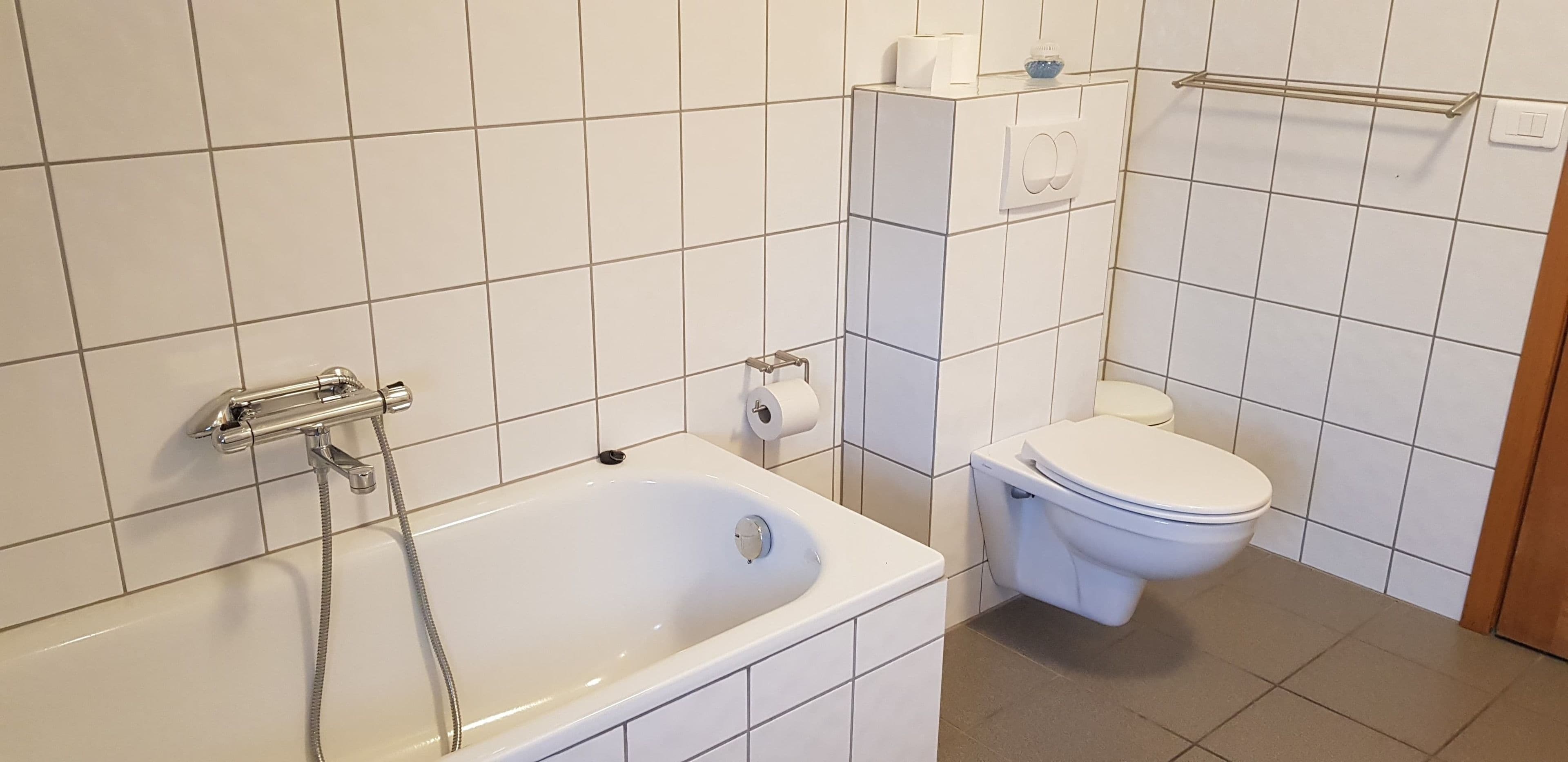 A bathroom with a bathtub, toilet, and a towel rack.