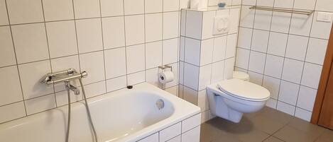 A bathroom with a bathtub, toilet, and a towel rack.