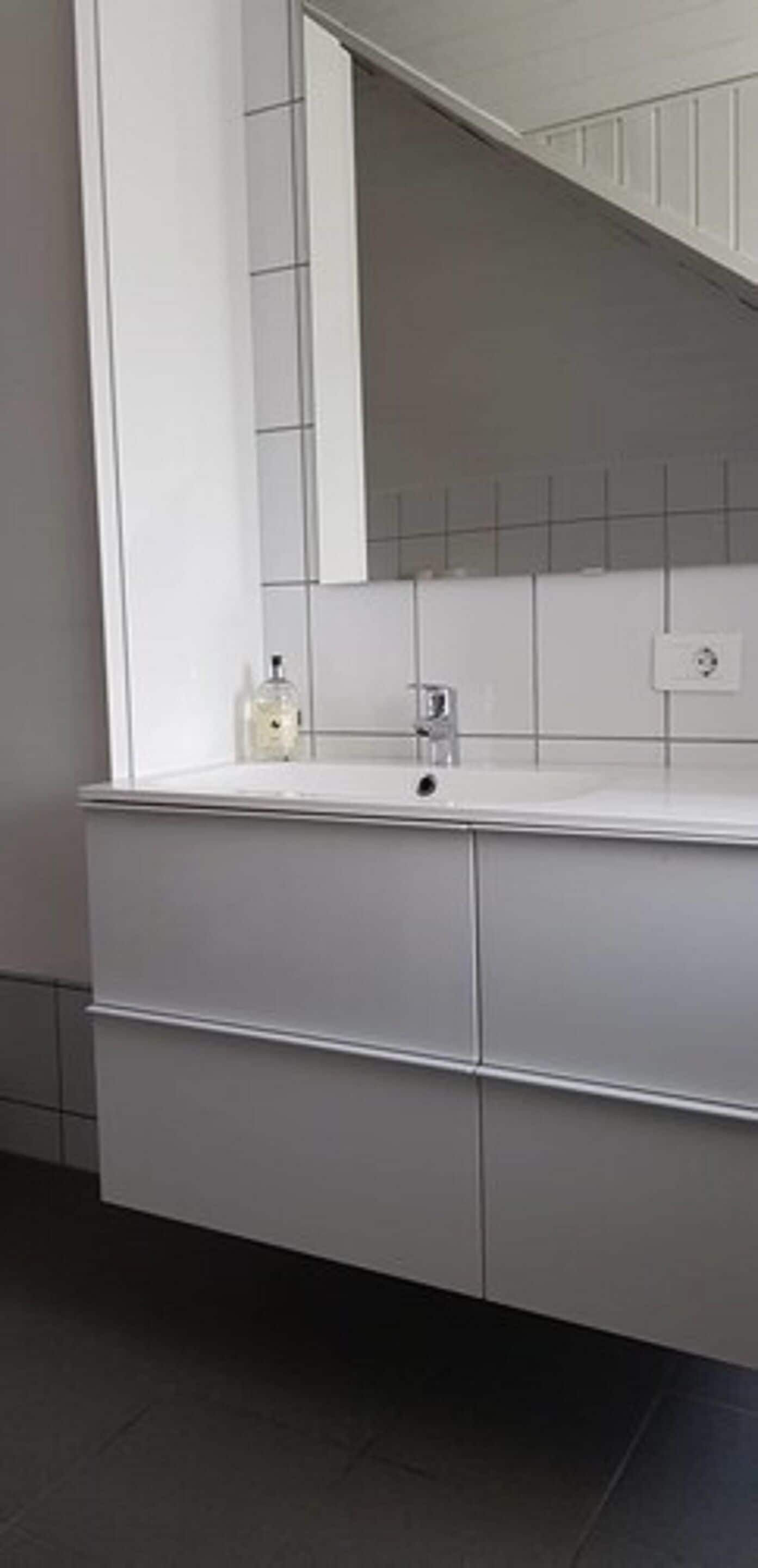 A bathroom with a white vanity, a mirror, and a sink.
