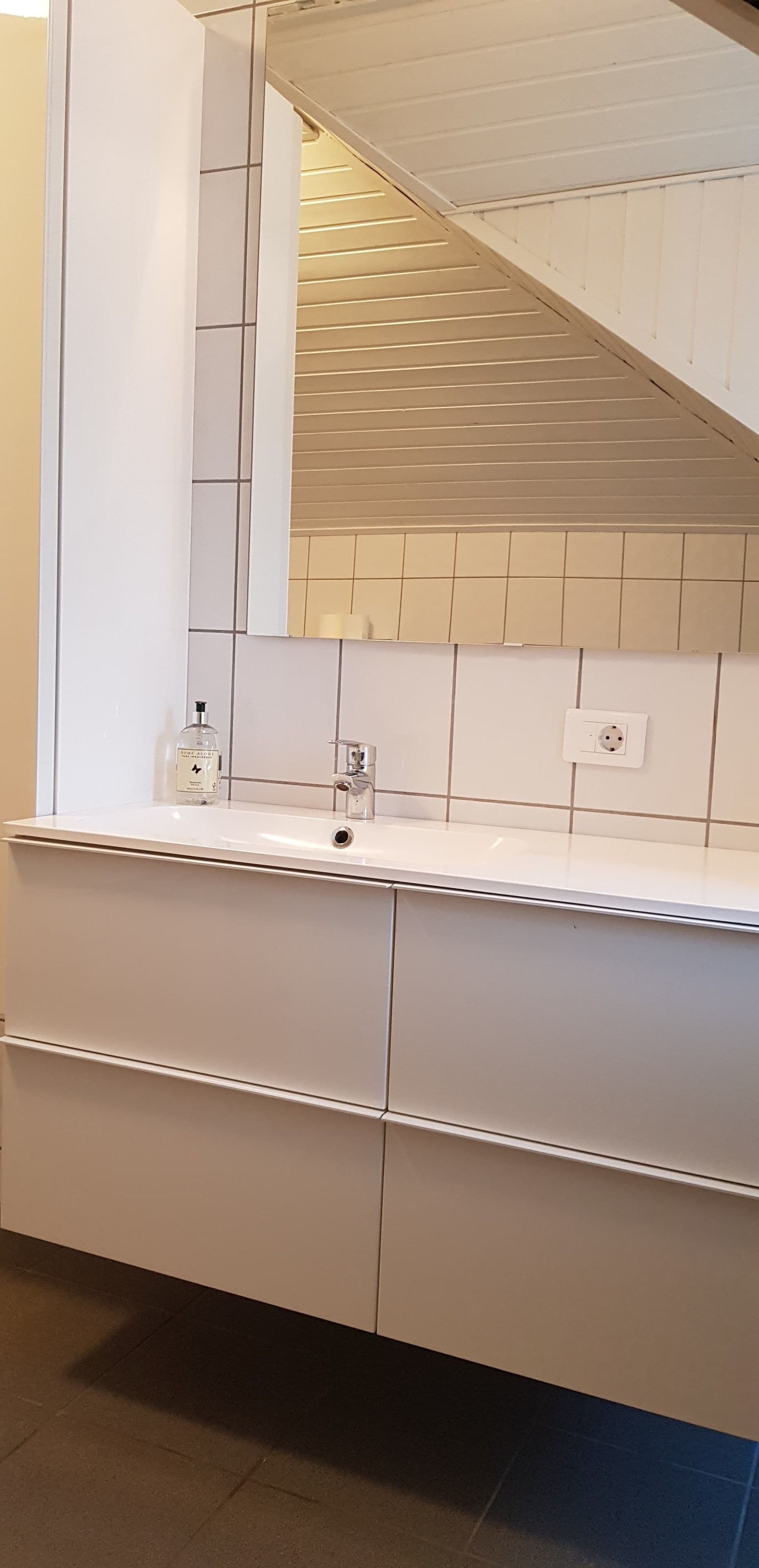 A bathroom with a white vanity, a mirror, and a tiled backsplash.