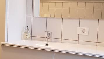 A bathroom with a white vanity, a mirror, and a tiled backsplash.