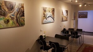Een vergaderruimte met een tafel, stoelen en abstracte schilderijen aan de muur.