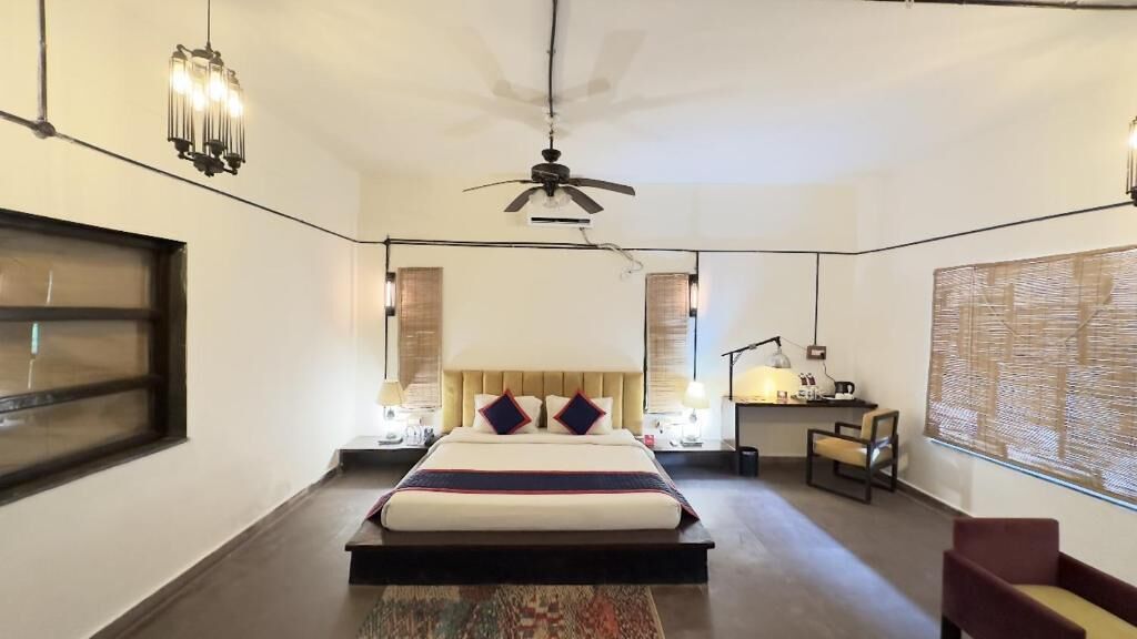 A hotel room with a large bed, bedside lamps, a ceiling fan, and a view of the outside through the window.