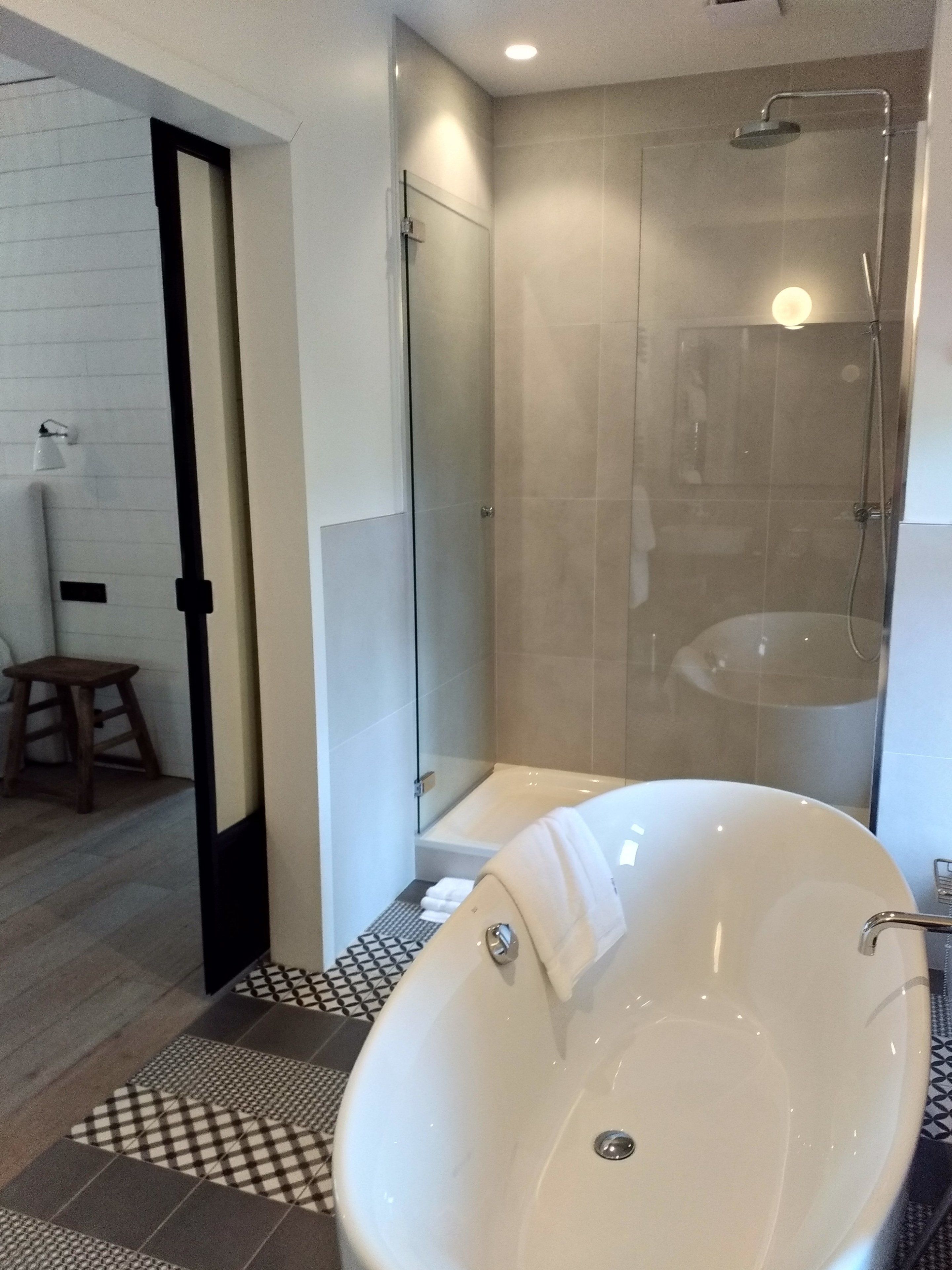 A modern bathroom with a freestanding bathtub, a glass-enclosed shower, and a small wooden stool.