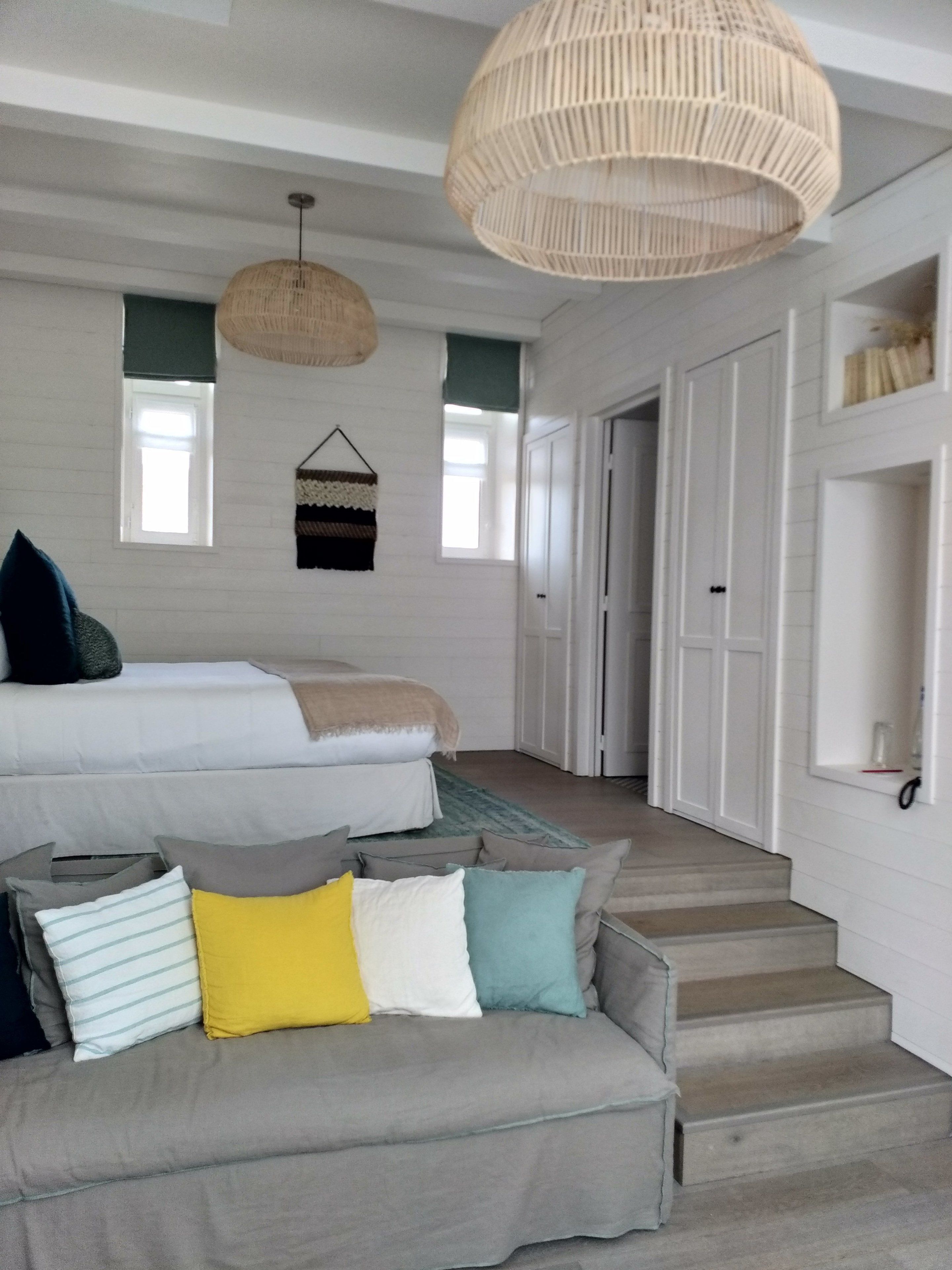 Une chambre moderne avec un grand lit, un canapé et un escalier menant à une autre pièce.