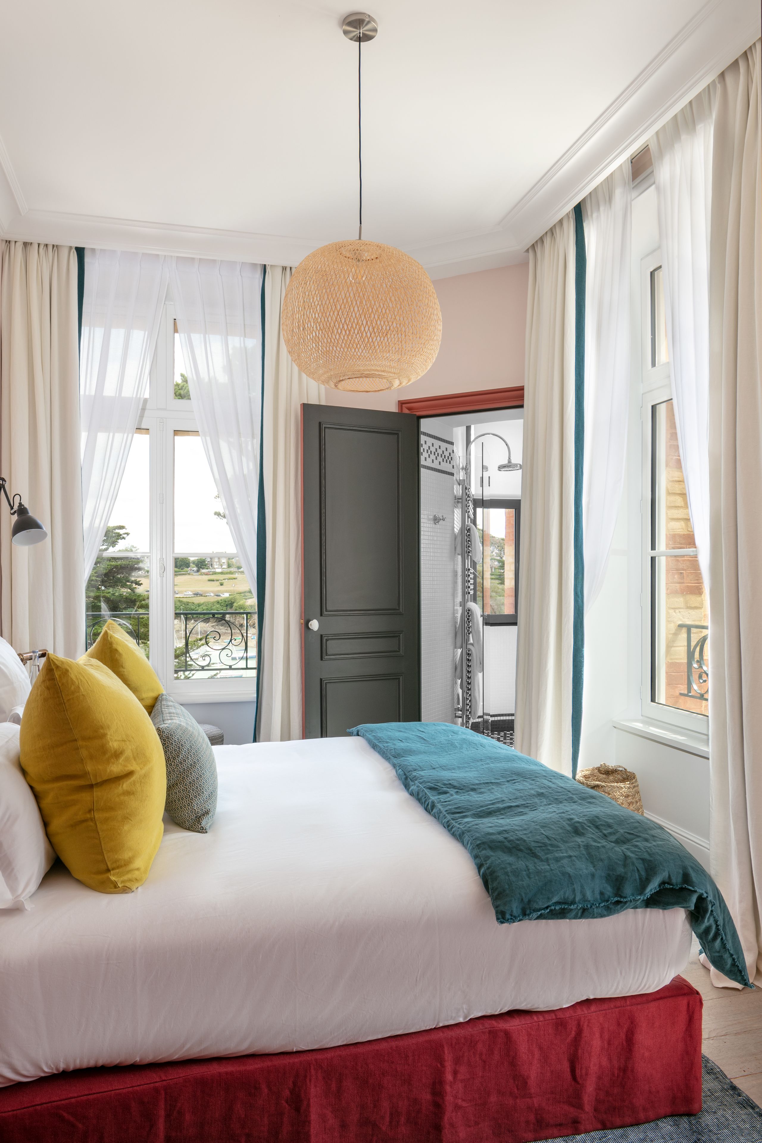 A bedroom with a bed, a view of the outside, and a door to a bathroom.