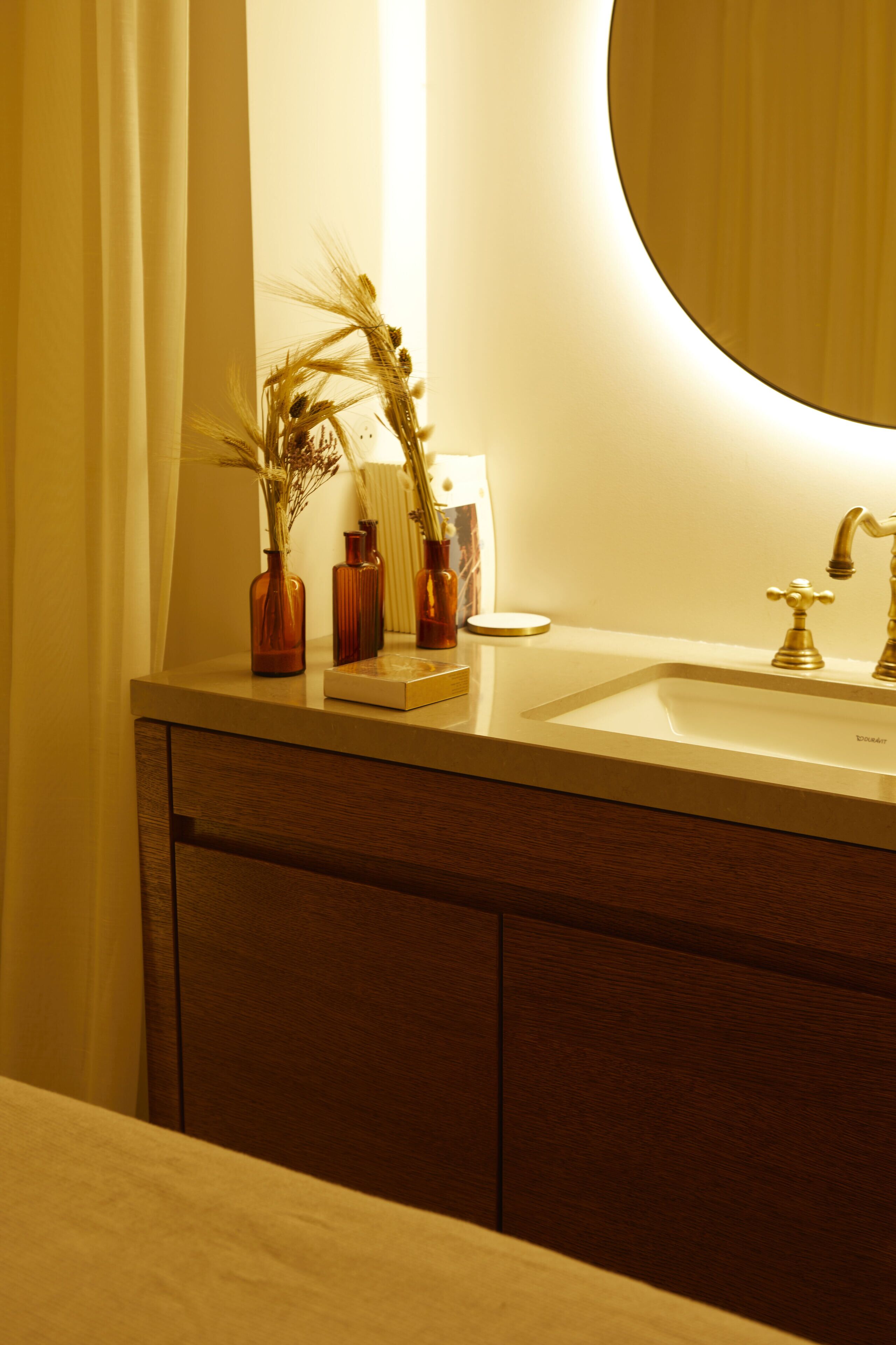 A bathroom with a sink, mirror, and decorative vases.