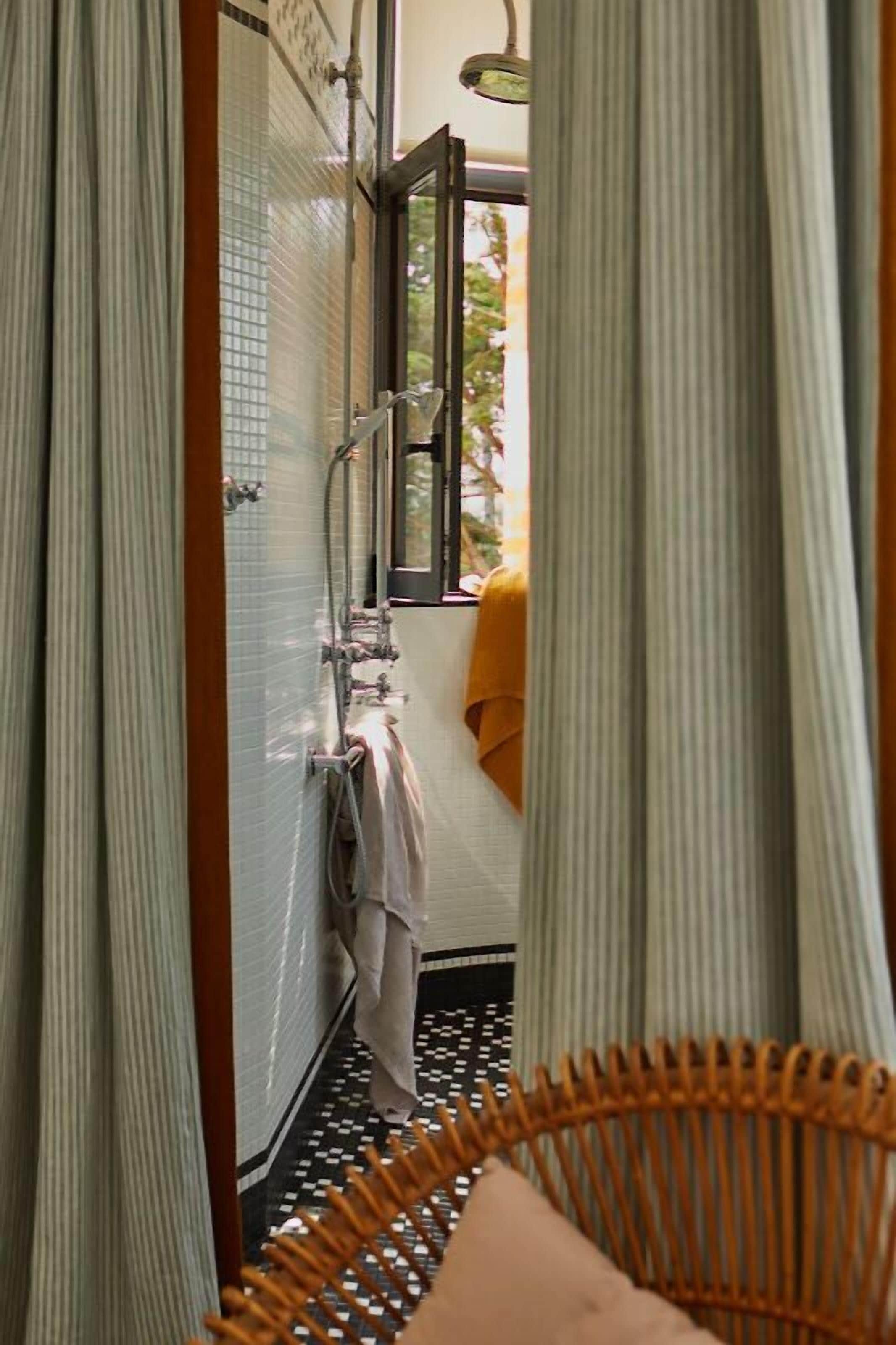 Une salle de bain avec une douche, un porte-serviettes et une fenêtre avec des rideaux.
