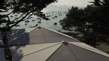 A beachside terrace with umbrellas and chairs, overlooking a calm sea with boats.