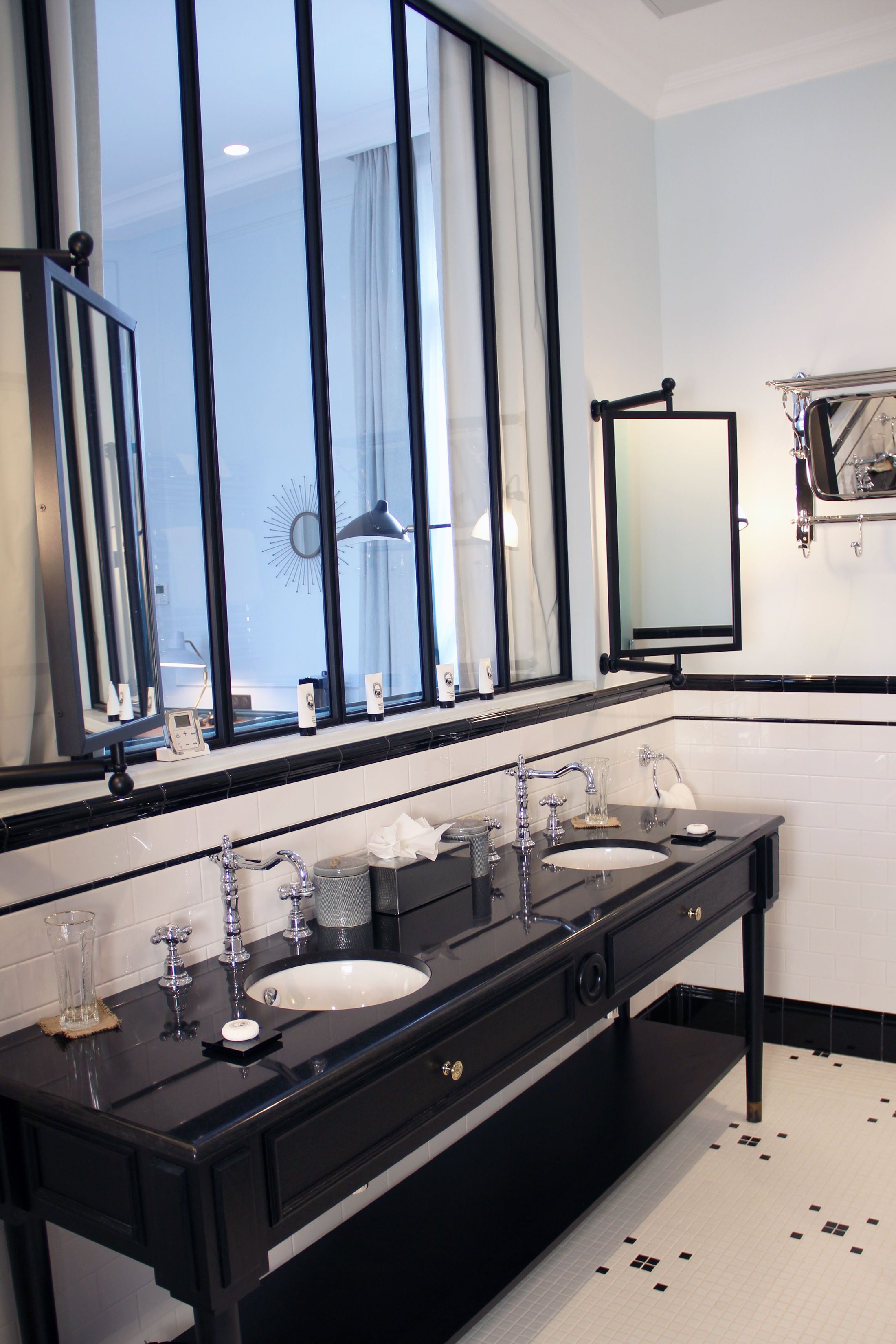 A modern bathroom with two sinks, a large mirror, and a window with curtains.