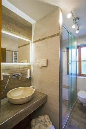 A modern bathroom with a large mirror, a round sink, and a glass shower enclosure. - Ferienhäuser Werdenfels (Mittenwald)