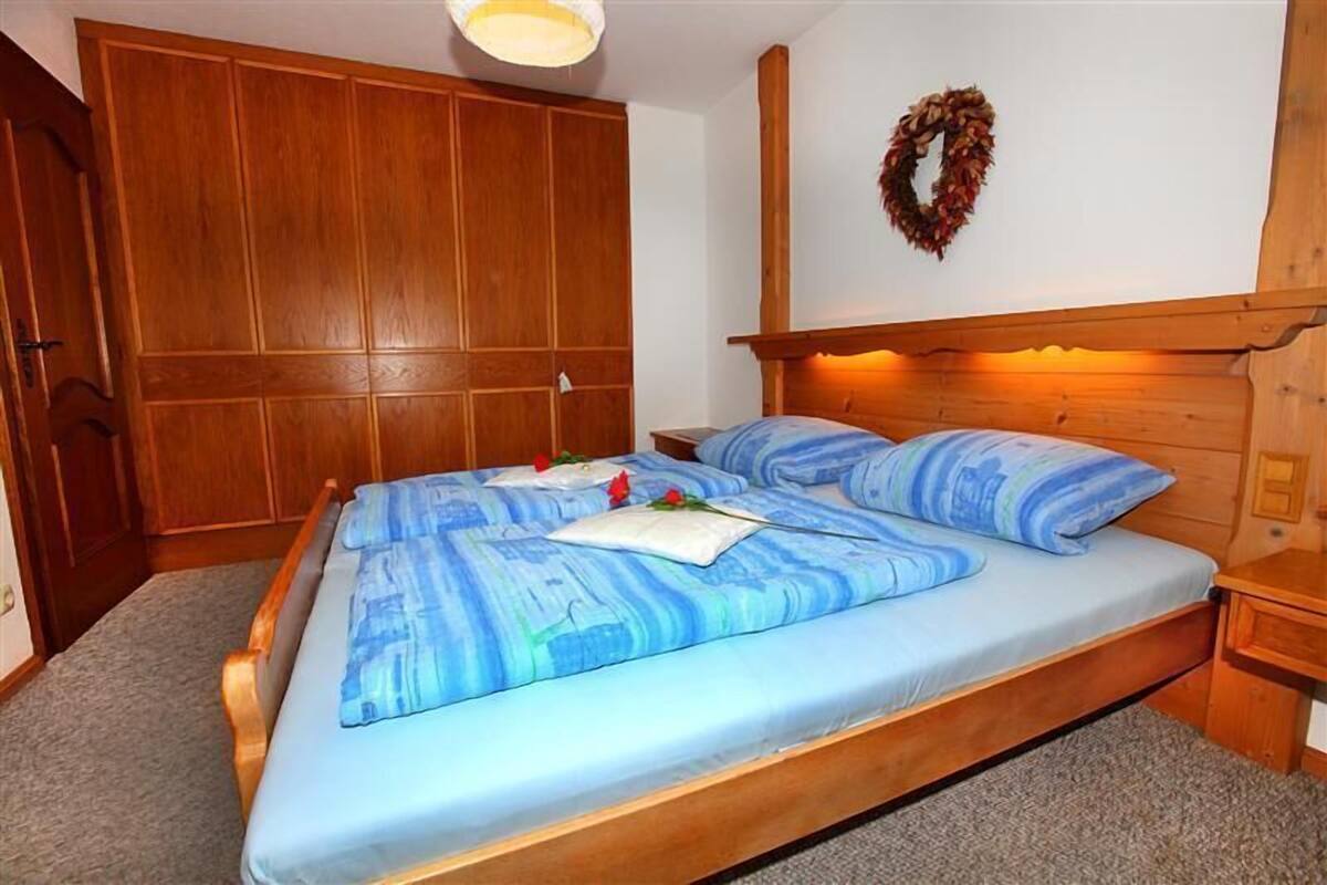 Une chambre à coucher avec un lit en bois, une armoire et une couronne décorative accrochée au mur.