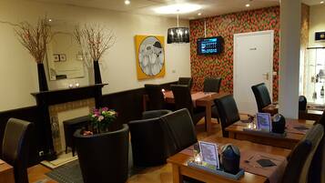 Vestíbulo de hotel con recepción, zona de estar y una pantalla de televisión.