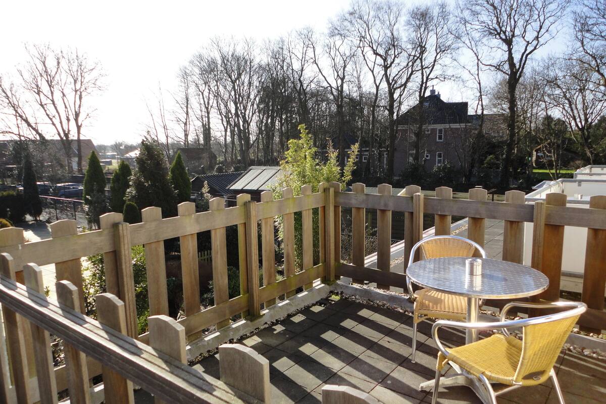 A patio with a wooden fence, a round table, and two wicker chairs.