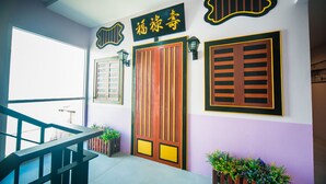A staircase leading to a room with a large wooden door and a sign above it. - Peranakan Boutique Hotel (Phuket)