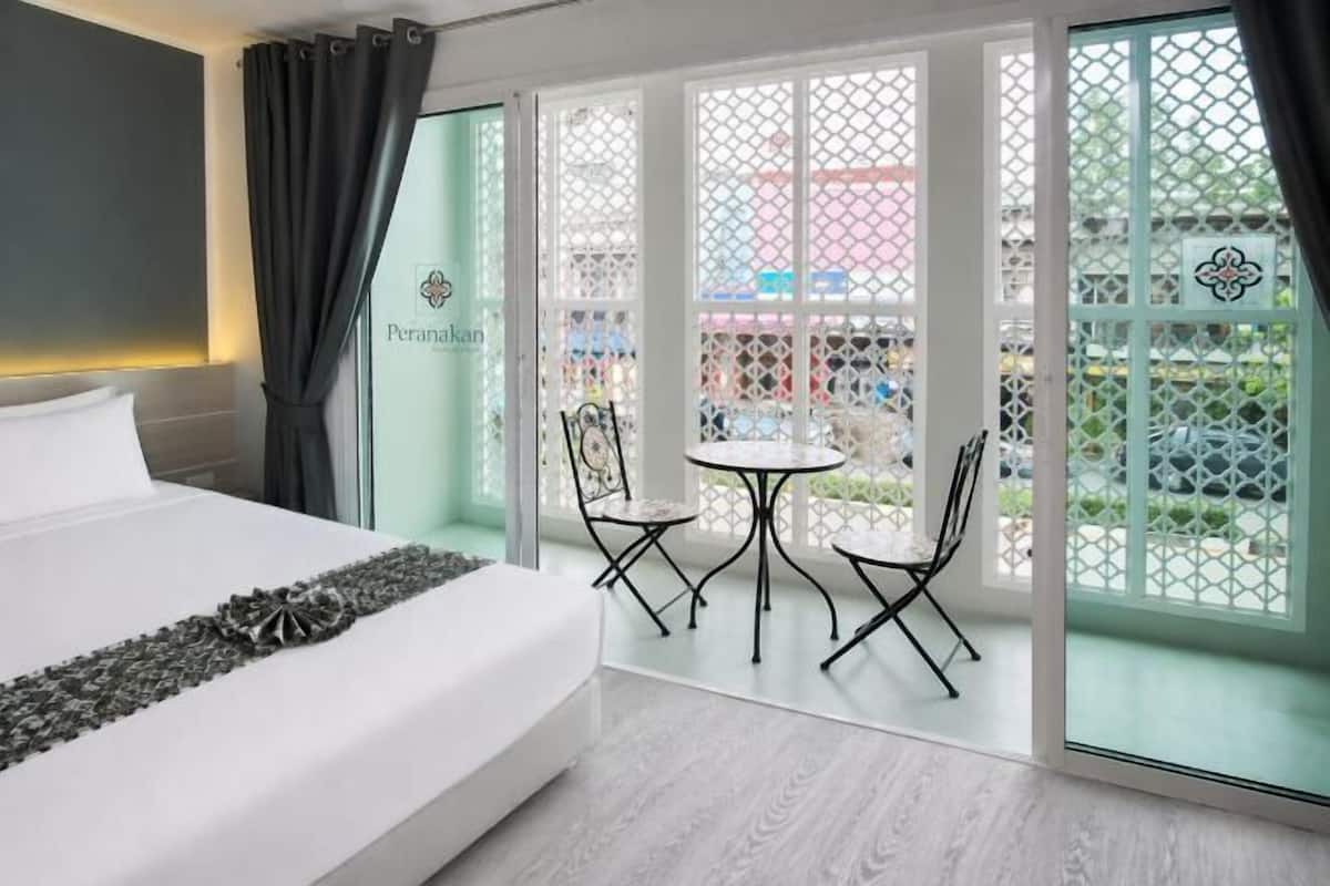 Una habitación de hotel con cama, una mesita con sillas y vistas a través de un ventanal.