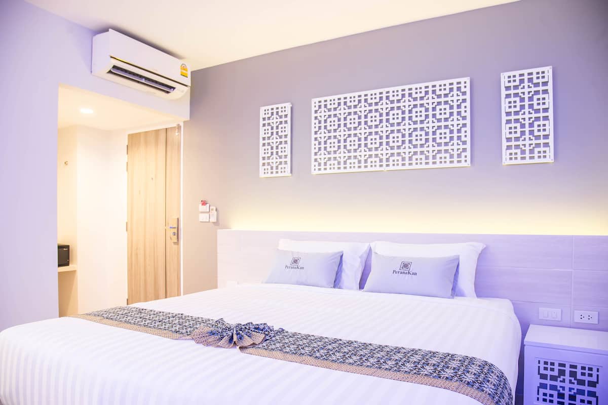 Une chambre d’hôtel équipée d’un lit, d’un système de climatisation et de panneaux muraux décoratifs.