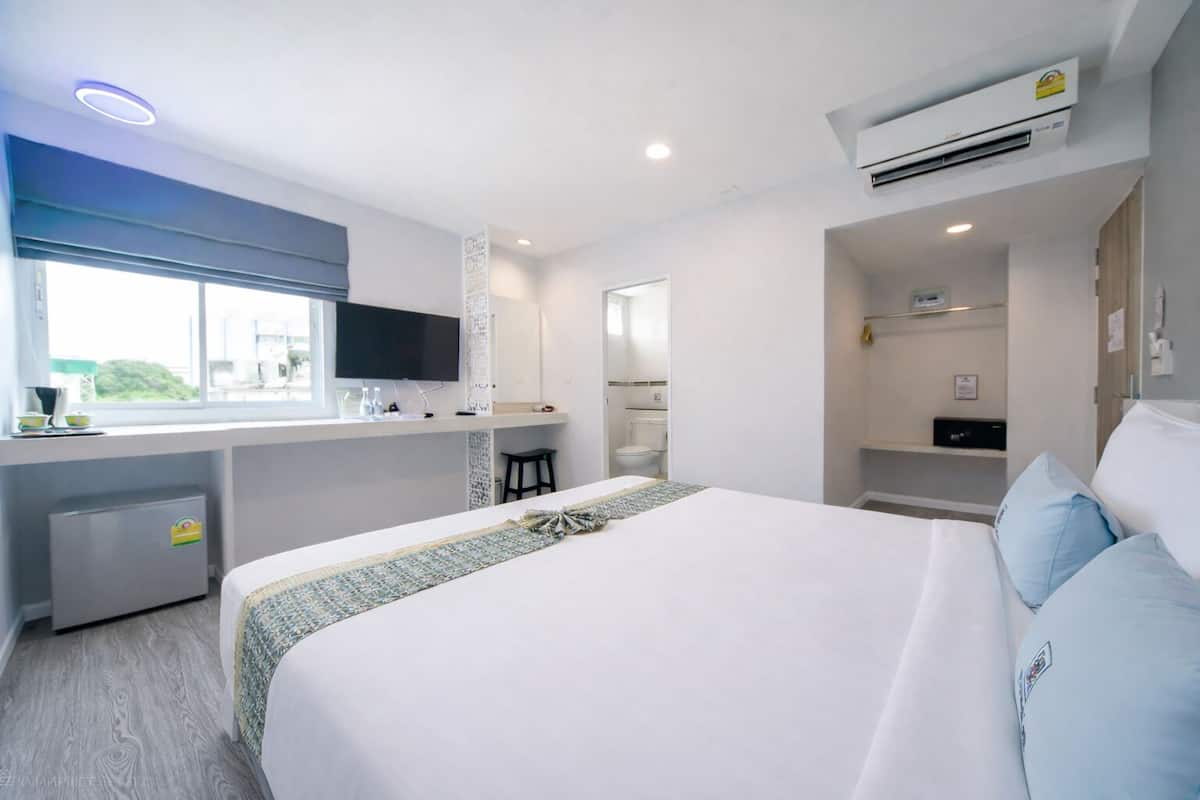 Une chambre d’hôtel avec un lit, un bureau, une télévision, une fenêtre et une salle de bain.
