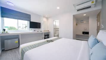 A hotel room with a bed, a desk, a TV, a window, and a bathroom.