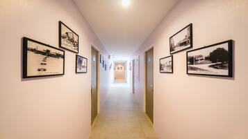 A hallway with framed historical photographs on the walls, leading to a bright room at the end.