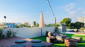 A rooftop terrace with a wooden deck, green artificial turf, and striped bean bag chairs. - Peranakan Boutique Hotel (Phuket)