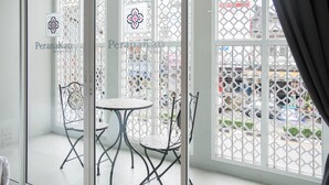 A room with a glass door, a small table, two chairs, and a decorative metal gate. - Peranakan Boutique Hotel (Phuket)