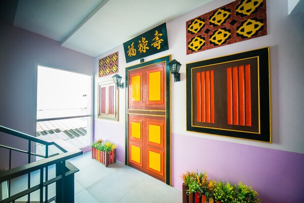 A hallway with a staircase, a door with a sign, and decorative wall art. - Peranakan Boutique Hotel (Phuket)