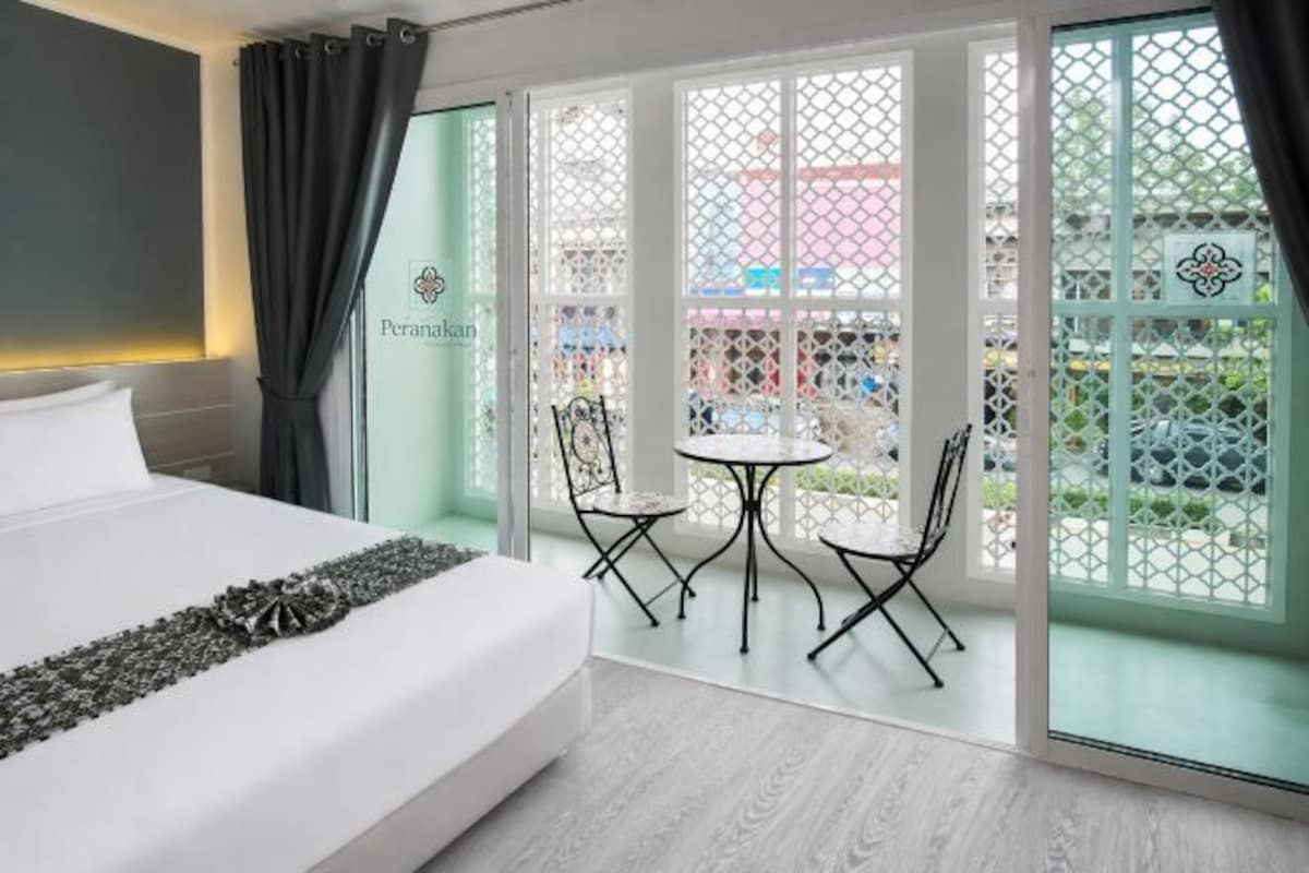 Una habitación de hotel con cama, una mesita con sillas y vistas a través de un ventanal.
