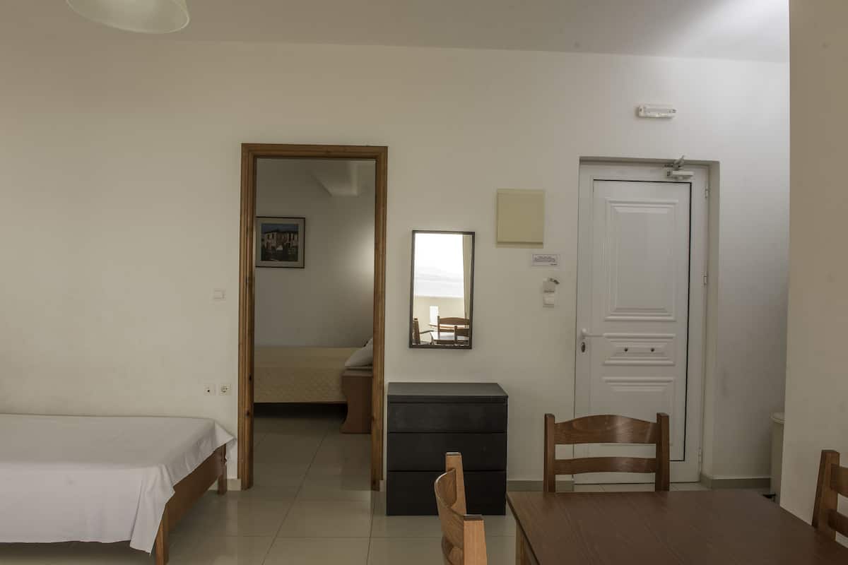Une chambre à coucher comprenant un lit, une chaise en bois, un bureau et une armoire.