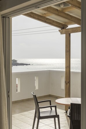 Uma varanda com vista para o mar, uma mesa redonda e duas cadeiras.