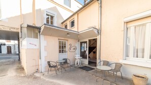 A building with a reception area, outdoor seating, and a staircase leading to an upper floor. - Hôtel Du Cygne (Auxerre)