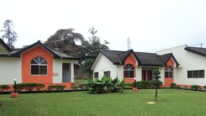 A row of white and orange buildings with a well-maintained lawn and potted plants. - The Town House (Ibadan)
