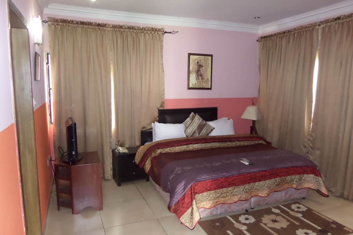 A hotel room with a bed, a nightstand, a lamp, a telephone, and a television.