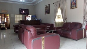 A living room with a sofa set, a television, a Coca-Cola refrigerator, and a painting on the wall. - The Town House (Ibadan)