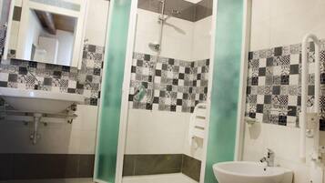 Une salle de bain avec un lavabo, un miroir, une douche et des murs carrelés.