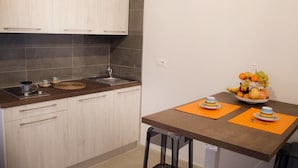 Une cuisine compacte équipée d’un évier, d’un plan de travail et d’un présentoir à fruits sur la table.